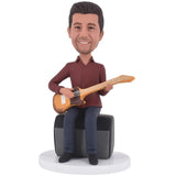 Custom bobblehead sitting with a guitar